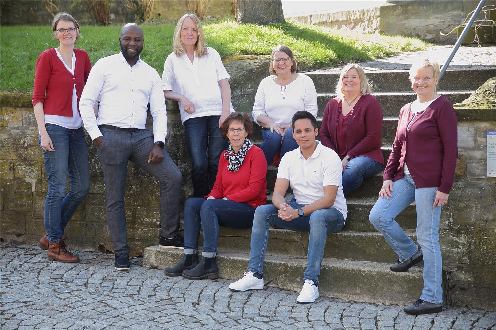 Team Beratungsdienste der Caritas Büren: Männer und Frauen stehend und sitzend auf einer grauen Stein-Treppe im Freien