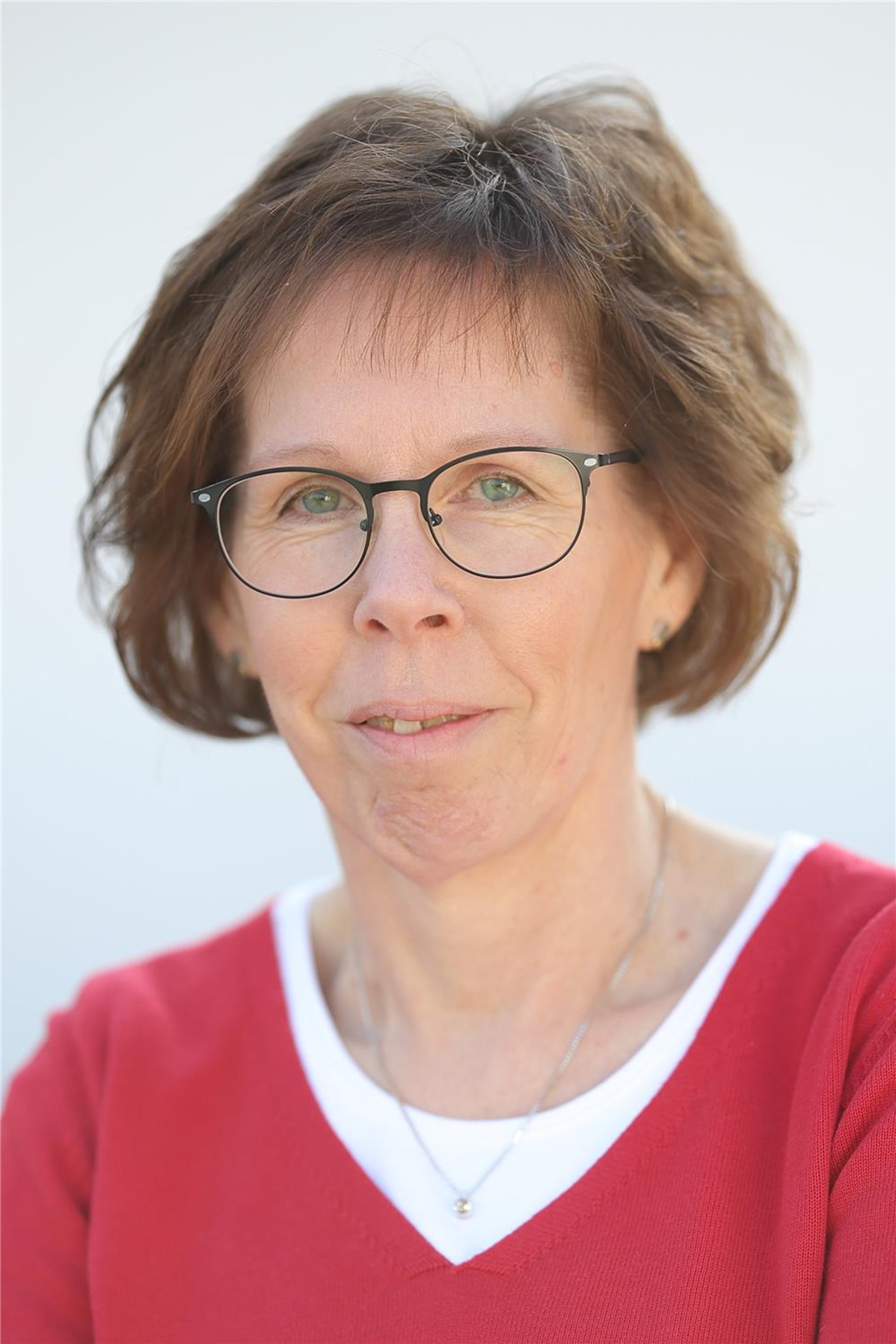 Frau mit Brille und kurzem Haar schaut in die Kamera