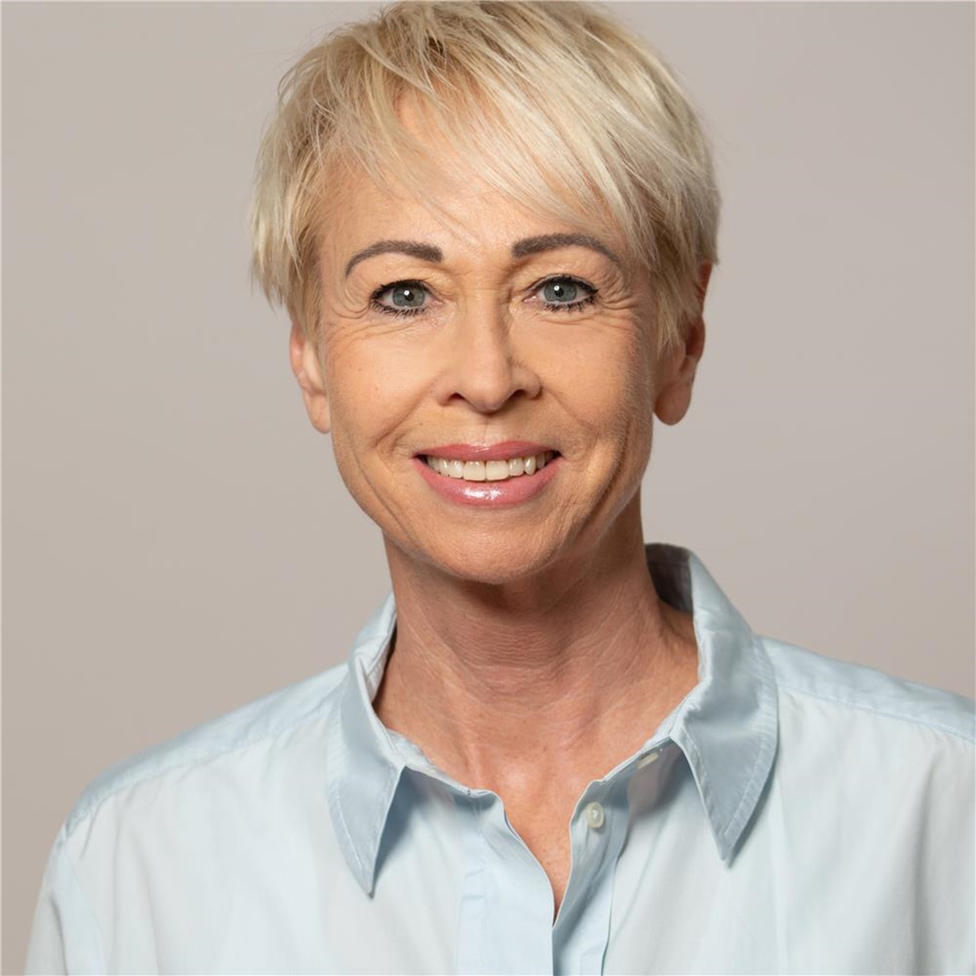 Portrait einer lächelnden Frau vor grauem Hintergrund