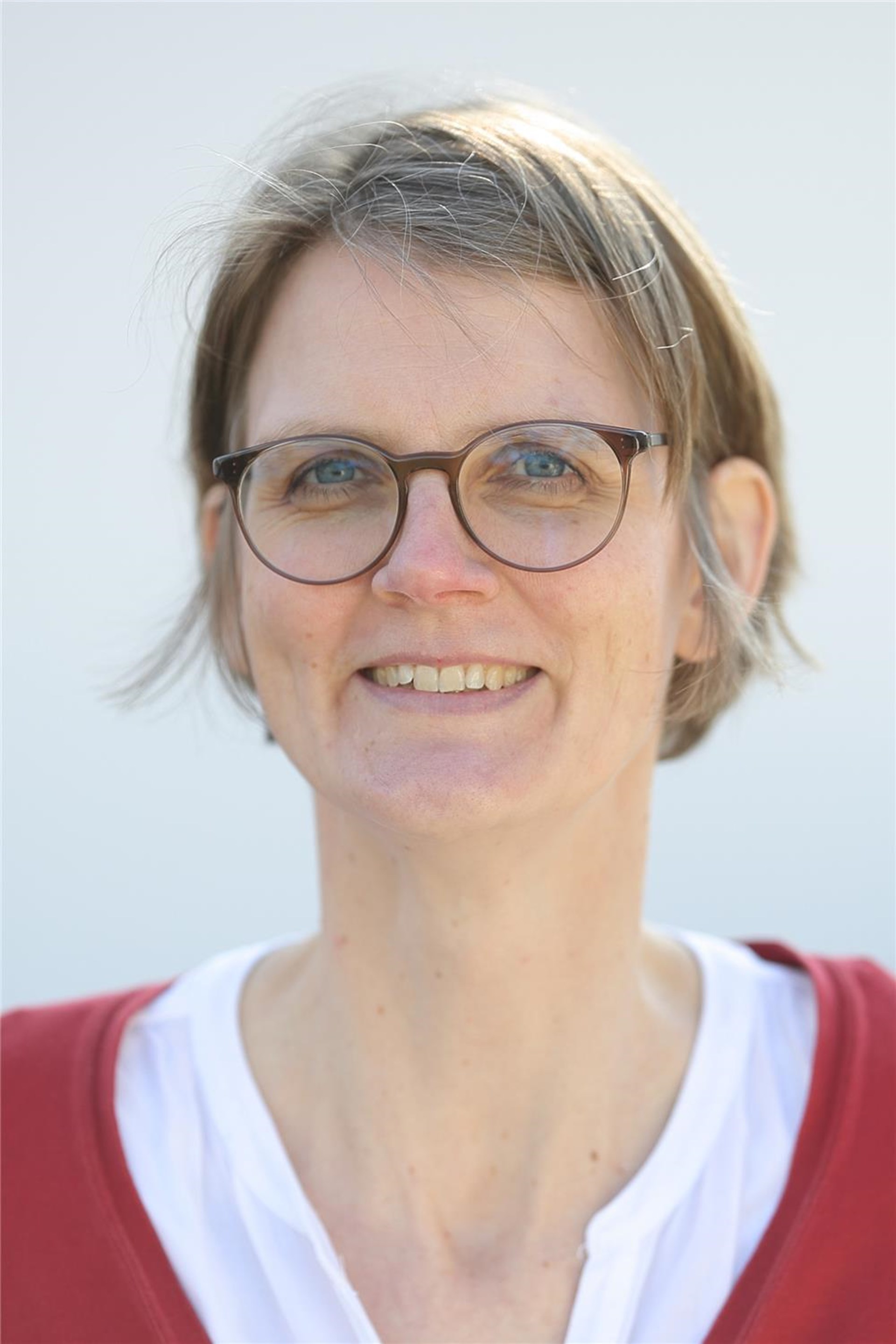 Frau mit Brille und kurzem Haar lächelt in die Kamera